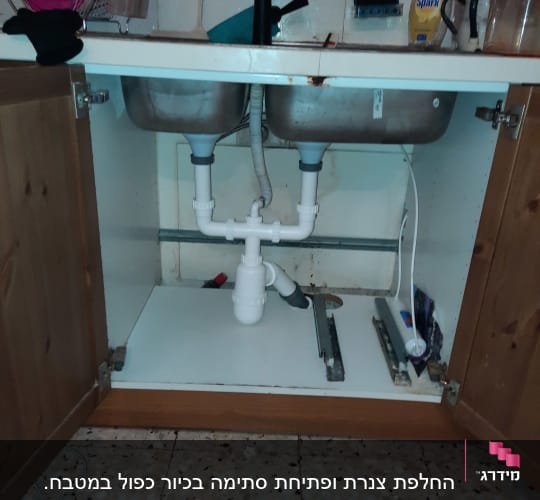 כיור כפול עם צנרת פלסטיק מתחת לארון מטבח